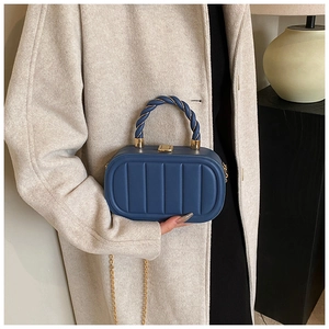 Detail of navy blue quilted chain box bag with golden hardware and rope handle