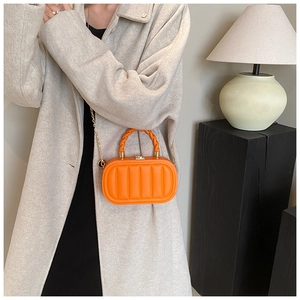 Detailed view of bright orange mini box bag featuring vertical quilted texture and chain strap