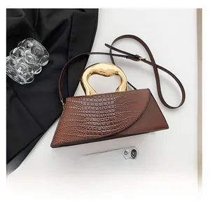 Detail of brown PU handbag with crocodile texture and sculptural gold metal handle