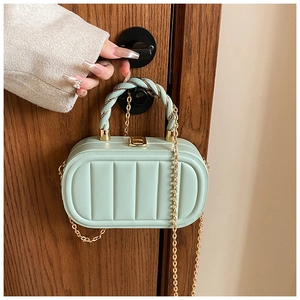 Detail of mint green quilted crossbody bag featuring twist handle and gold chain strap