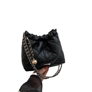 Classic black quilted drawstring handbag with gold chain strap and metal ball charms