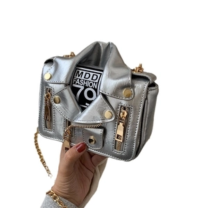 Silver biker jacket shaped mini crossbody bag with gold chain strap held by hand