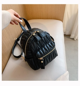 Detail of black wave quilted backpack with gold zippers and polished leather texture