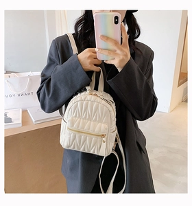Detail of white quilted faux leather mini backpack with golden metal zippers