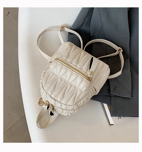 Detailed view of white quilted mini leather backpack with gold zippers and metal hardware