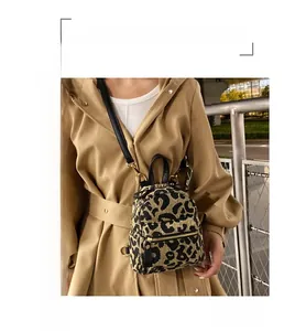 Mini leopard print backpack with gold hardware and black leather straps on a model