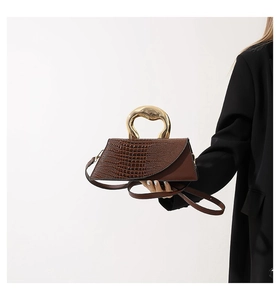 Detailed view of dark brown faux crocodile handbag with elegant gold metal handle
