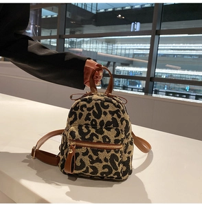 Detailed view of leopard print mini backpack with brown leather trim and metal zippers