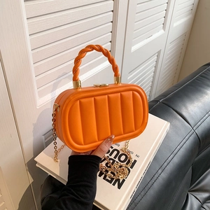 Bright orange quilted crossbody bag with a woven handle and gold chain shoulder strap