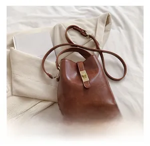 Gros plan du sac seau en cuir caramel avec fermoir tournant doré et fine bandoulière
