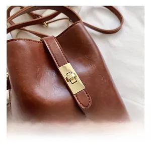 Gros plan d'un sac seau en cuir marron avec un fermoir rotatif métallique doré brillant