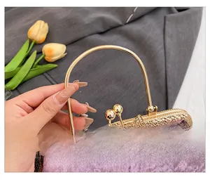 Detail of purple velvet evening bag featuring gold metal handle and rhinestone flower clasp