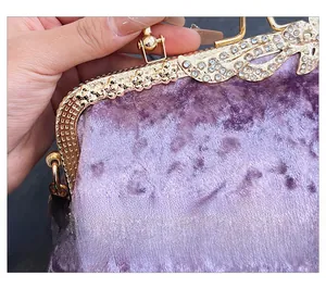 Close-up of purple velvet evening bag with gold metal frame and sparkling crystals