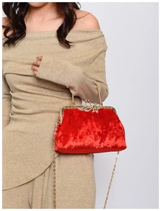 Detail of red velvet evening clutch with golden metal handle and crystal bow clasp