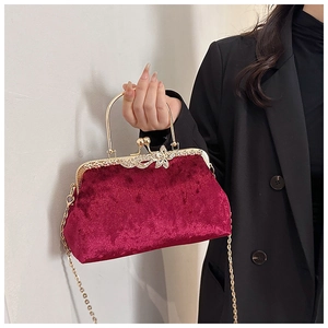 Close-up of burgundy velvet evening bag with gold metal frame and rhinestone floral clasp