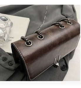 Detail of distressed brown leather shoulder bag with metal chain and vintage buckle