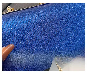 Detail of blue glitter fabric with vertical textures and gold metal frame on a small handbag