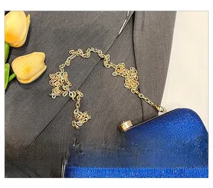 Detail of royal blue glitter evening clutch bag with golden metal chain strap accessory