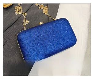Close-up of navy blue sequined evening clutch bag with gold chain and wavy texture