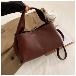 Detail of dark brown faux leather handbag with lychee texture and vertical stitching
