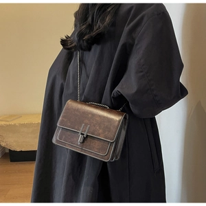 Detail of vintage brown leather crossbody bag with silver buckle and contrast stitching