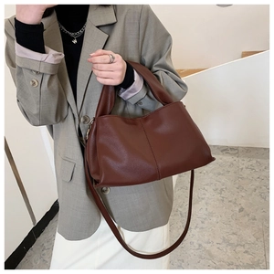 Detail of dark brown leather handbag with pebble texture and adjustable shoulder strap
