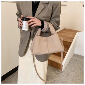 Elegant beige gathered handbag worn by model with professional grey suit and skirt