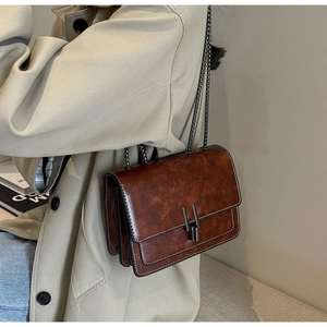 Close-up of retro brown wax leather shoulder bag with vintage metal buckle and chain strap