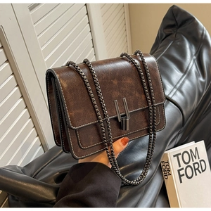 Detail of vintage brown cracked leather texture and metallic H-lock on the chain bag