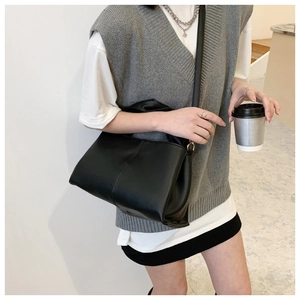 Detail of black pebbled leather texture on a high-capacity shoulder bag with slim strap