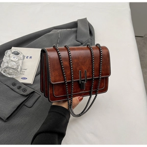 Detail view of vintage brown envelope bag with metallic chain and vertical metal clasp