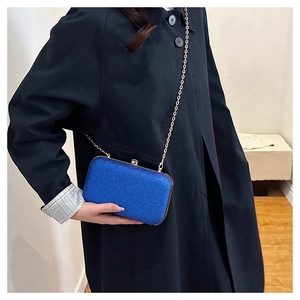 Close-up of royal blue sequin evening bag with gold metal frame and delicate chain strap