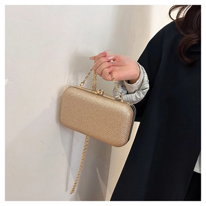 Detail of sparkling gold sequin evening clutch bag with jeweled clasp and chain strap