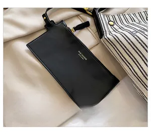 Détail de la pochette en cuir noir avec zip doré et du sac en toile à rayures