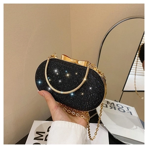 Détail de la pochette de soirée à paillettes noires avec fermoir nœud doré et chaîne