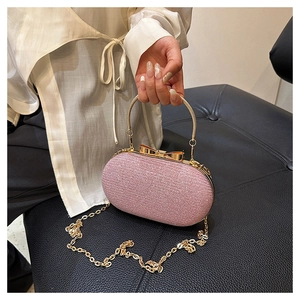 Détail d'une pochette rose pailletée avec fermoir nœud doré et chaîne métallique fine
