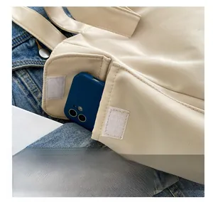 Detail view of canvas tote bag side pocket with velcro closure holding a mobile phone