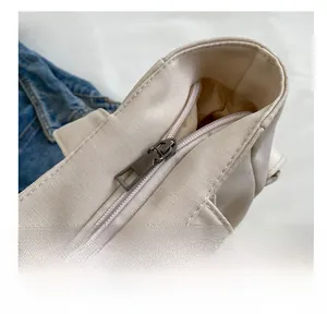 Detail showing smooth metal zipper closure and inner lining of the beige canvas tote bag
