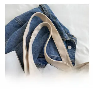 Detail shot of a beige canvas tote bag showing the reinforced wide shoulder strap design