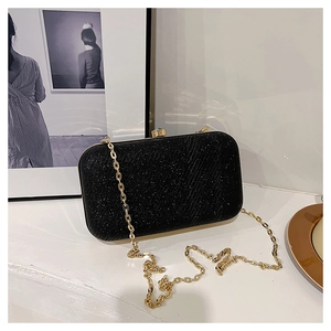 Elegant black glitter evening clutch bag with gold chain strap on a white surface