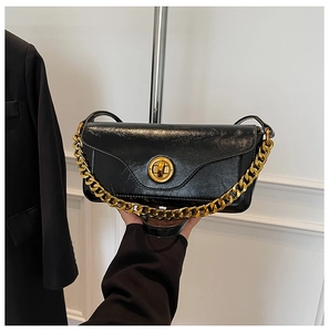 Detail of black wrinkled leather mini bag with gold chain strap and round turn-lock