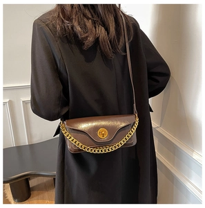 Detailed view of brown leather crossbody bag with gold chain and round turn-lock