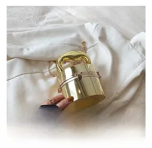 Detailed view of a gold cylindrical metal evening bag with chunky handle and ball lock clasp