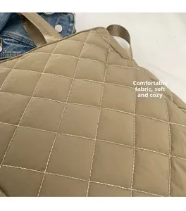 Close-up of khaki diamond quilted nylon fabric and soft padded carrying handles