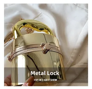 Detail showing the golden mirror texture, sphere lock, and thick ring handle of the handbag
