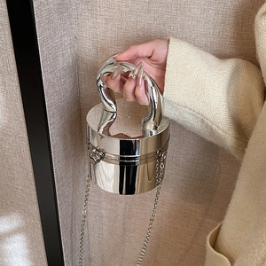 Detail of silver cylindrical metal handbag with curved handle and fine chain strap