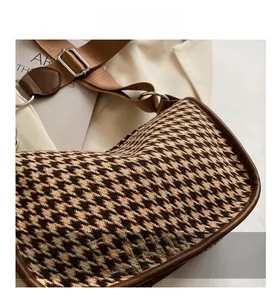 Detail of houndstooth fabric crossbody bag with brown leather trim and nylon strap