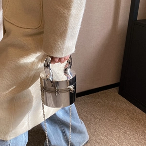 Detail of silver cylindrical handbag with polished metal finish and U-shaped handle