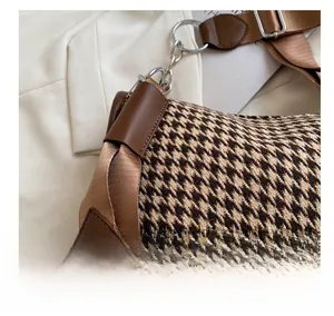 Close-up of brown houndstooth fabric and dark leather trim on a chic crossbody bag