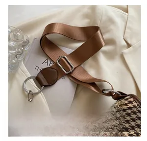 Detail of adjustable nylon strap and silver hardware on brown houndstooth shoulder bag